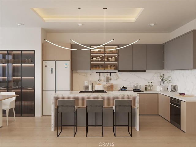 kitchen featuring gray cabinets, a kitchen island, light wood-type flooring, and backsplash