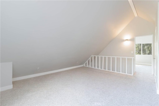 additional living space featuring light colored carpet and vaulted ceiling