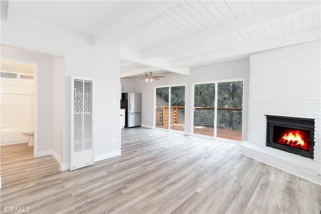 unfurnished living room with beam ceiling, ceiling fan, a fireplace, and light hardwood / wood-style floors