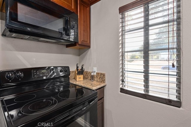 kitchen with light stone countertops, a wealth of natural light, and black appliances