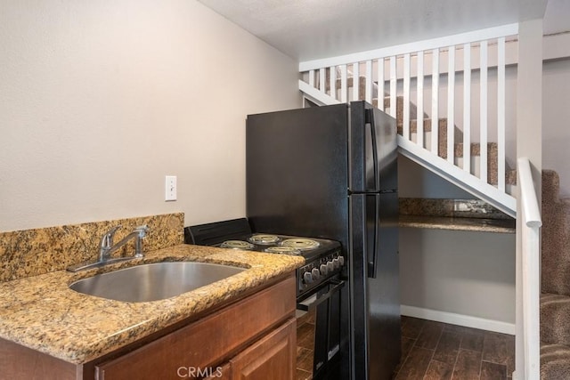 kitchen with light stone counters, sink, stainless steel range with electric cooktop, and dark hardwood / wood-style floors