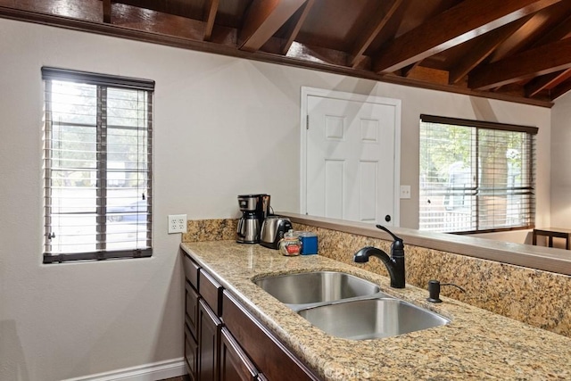 kitchen with sink, light stone countertops, and a healthy amount of sunlight