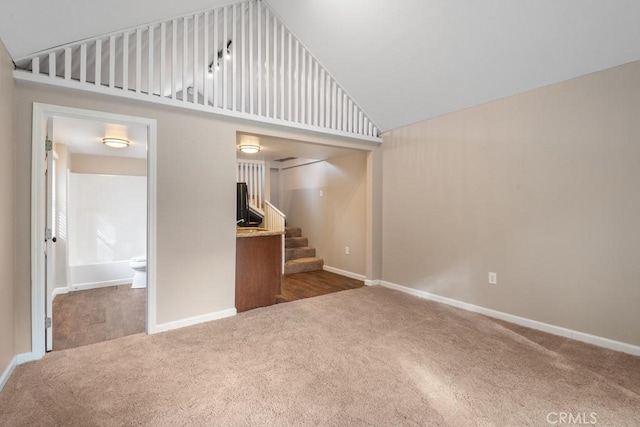 unfurnished living room with high vaulted ceiling and dark carpet