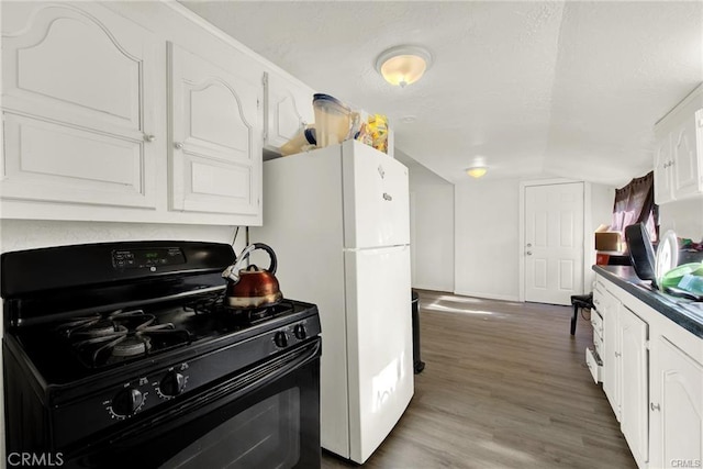 kitchen with white cabinets, black gas range oven, dark hardwood / wood-style flooring, and white fridge