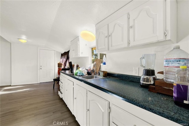 kitchen featuring vaulted ceiling, white cabinetry, and dark hardwood / wood-style floors