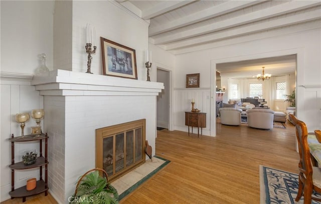 living room with hardwood / wood-style flooring, a notable chandelier, and beamed ceiling