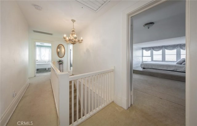 hallway featuring light carpet and an inviting chandelier