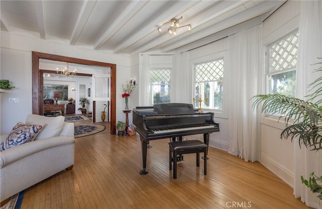 miscellaneous room featuring beamed ceiling, a chandelier, and light hardwood / wood-style flooring