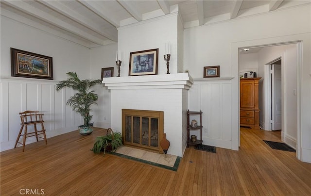 sitting room with beam ceiling, a fireplace, and hardwood / wood-style flooring