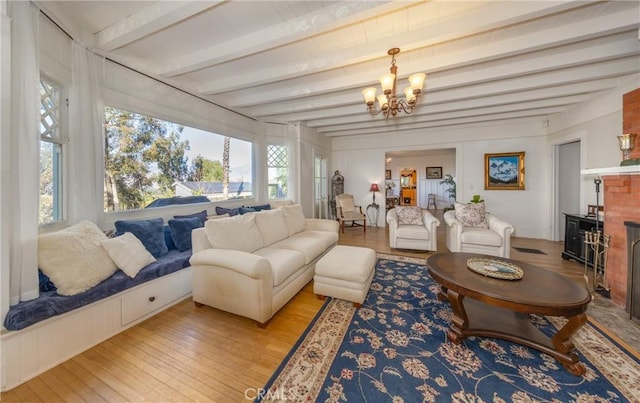 living room with beamed ceiling, light wood-type flooring, and an inviting chandelier