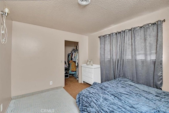 bedroom with light carpet, a closet, a spacious closet, and a textured ceiling