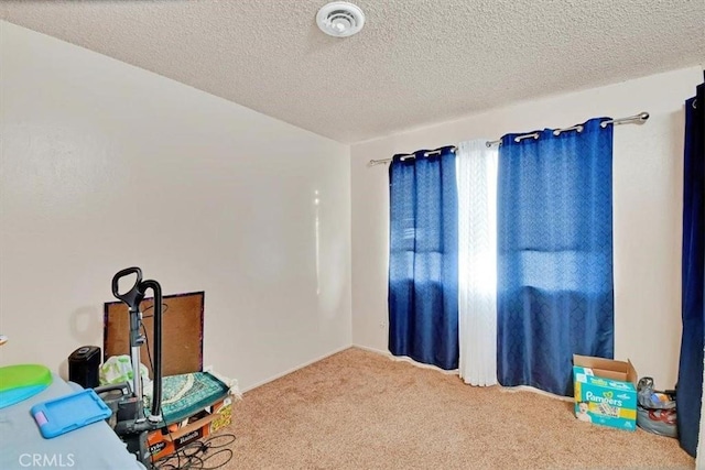 misc room with carpet floors, visible vents, and a textured ceiling