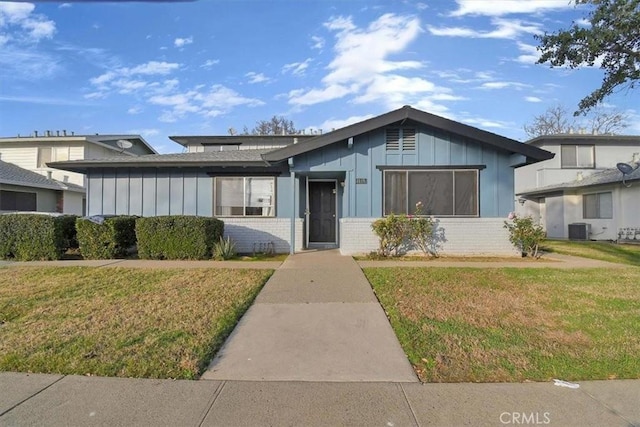 view of front of property with central AC and a front lawn