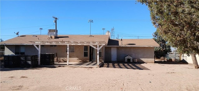 rear view of house with central AC and a pergola