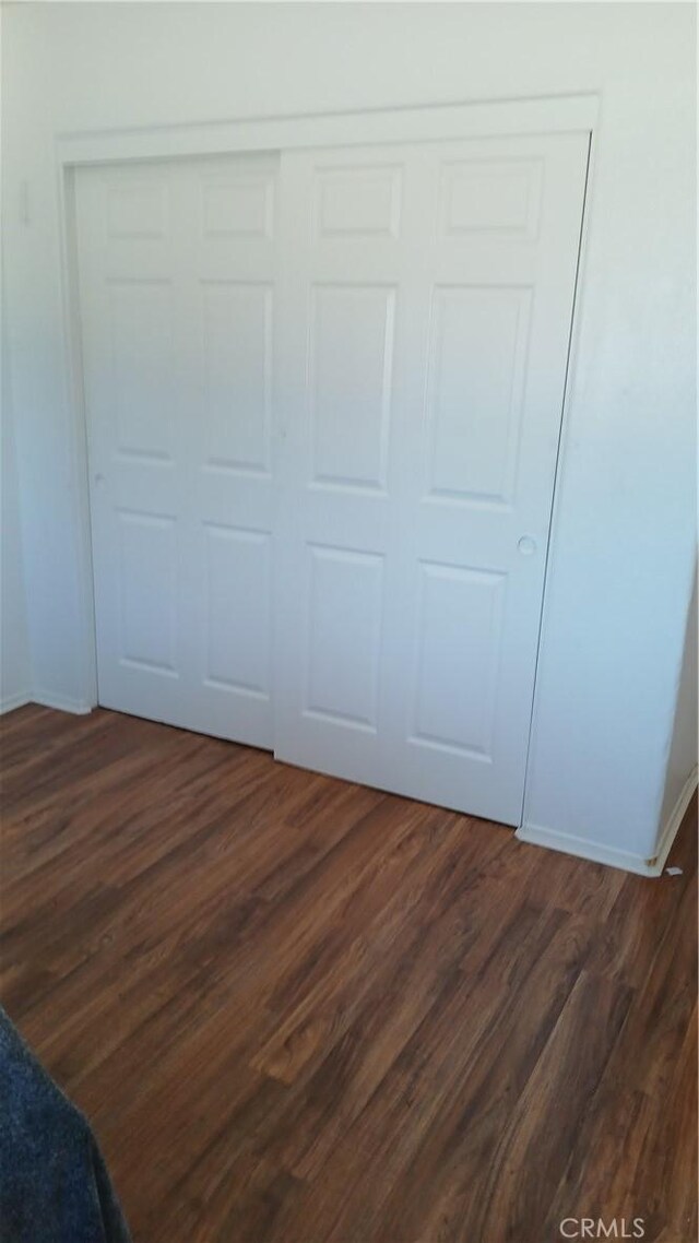 unfurnished bedroom with a closet and dark hardwood / wood-style floors