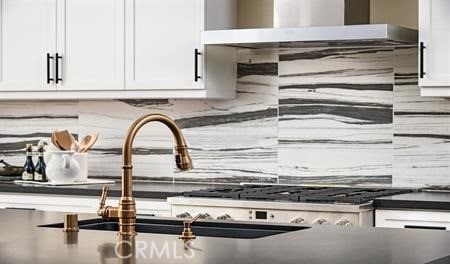 details featuring white cabinets, decorative backsplash, and wall chimney range hood