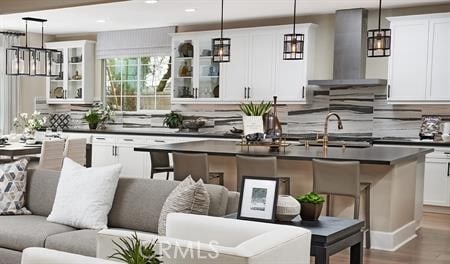 kitchen featuring white cabinets, wall chimney exhaust hood, a center island, and decorative light fixtures