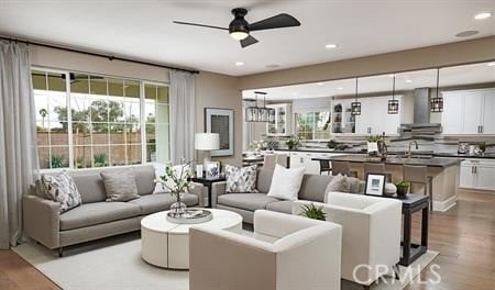 living room with ceiling fan, sink, and light wood-type flooring