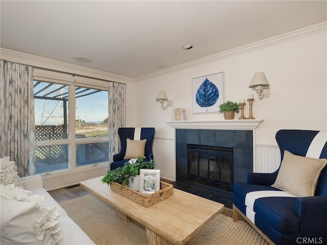 living room with a tiled fireplace, wood-type flooring, and ornamental molding