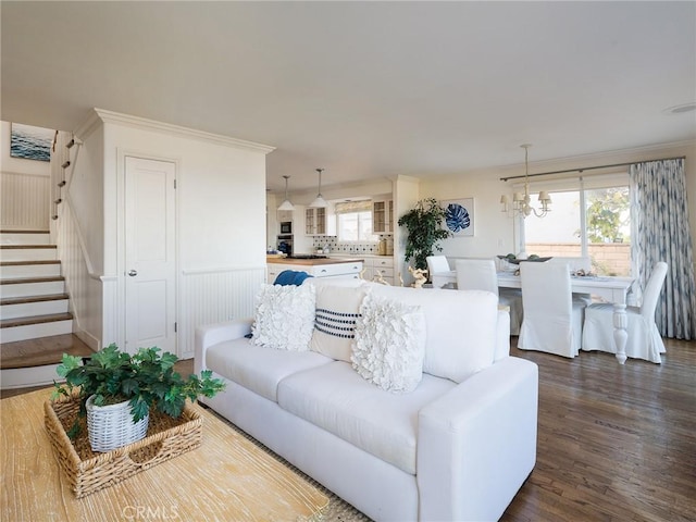 living room featuring dark hardwood / wood-style flooring, a notable chandelier, and ornamental molding