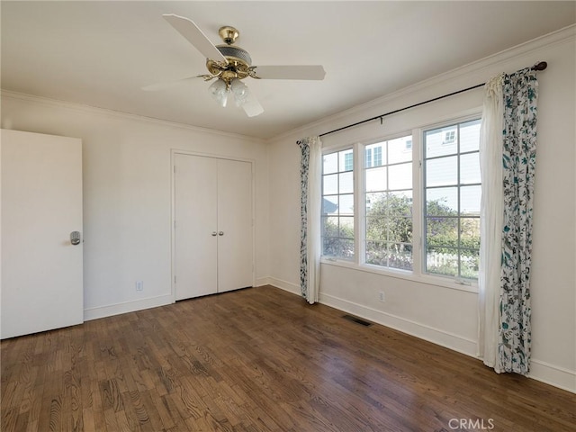 unfurnished bedroom with a closet, dark hardwood / wood-style floors, ceiling fan, and ornamental molding