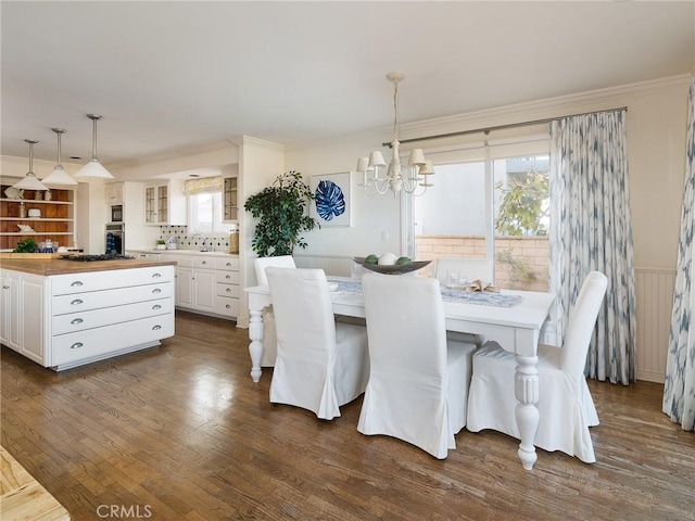 dining room featuring dark hardwood / wood-style flooring, ornamental molding, and a chandelier