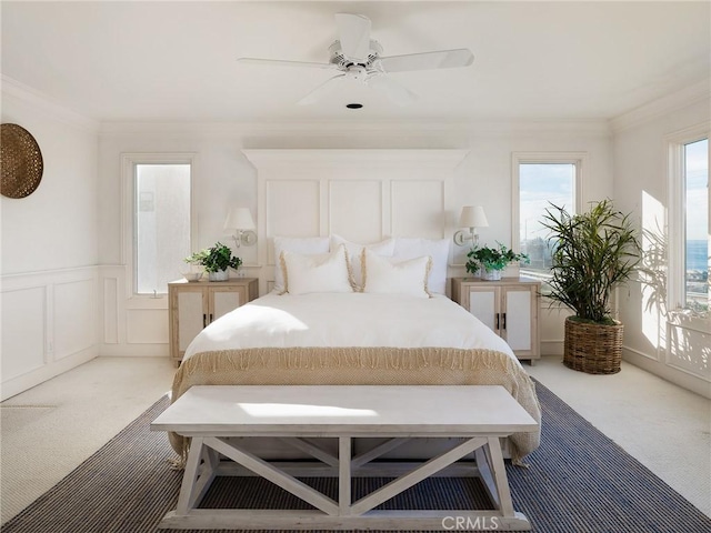 carpeted bedroom featuring ceiling fan and crown molding