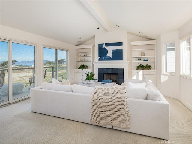 carpeted living room featuring vaulted ceiling with beams, a healthy amount of sunlight, and a tiled fireplace