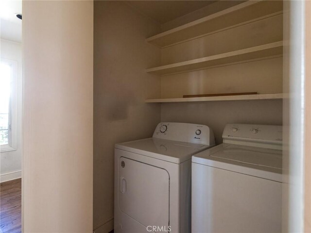 clothes washing area with hardwood / wood-style floors and washer and clothes dryer