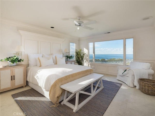 bedroom with ceiling fan, a water view, ornamental molding, and light carpet