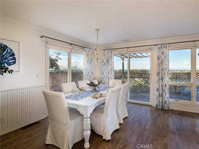 dining area featuring a chandelier, dark hardwood / wood-style flooring, a wealth of natural light, and ornamental molding