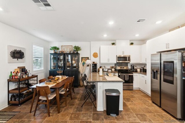 kitchen featuring white cabinetry, a breakfast bar, a center island, and appliances with stainless steel finishes