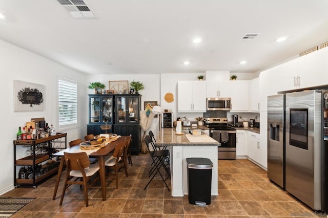 kitchen featuring a kitchen breakfast bar, stainless steel appliances, white cabinets, and a kitchen island