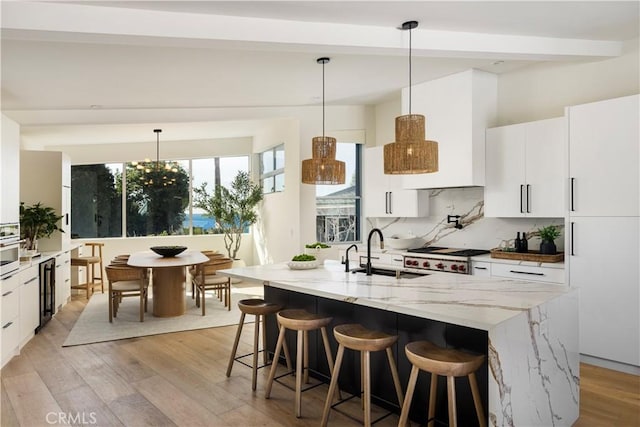 kitchen with a sink, a kitchen breakfast bar, light wood-style floors, backsplash, and modern cabinets