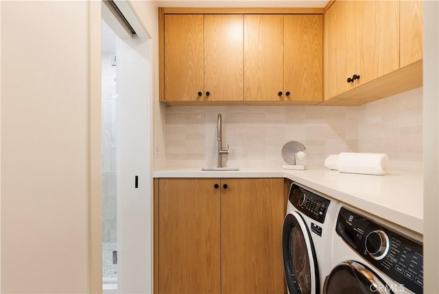 washroom featuring cabinet space, a sink, and washing machine and clothes dryer