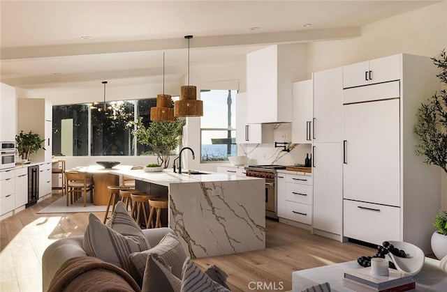 kitchen featuring wall chimney exhaust hood, modern cabinets, appliances with stainless steel finishes, and a sink