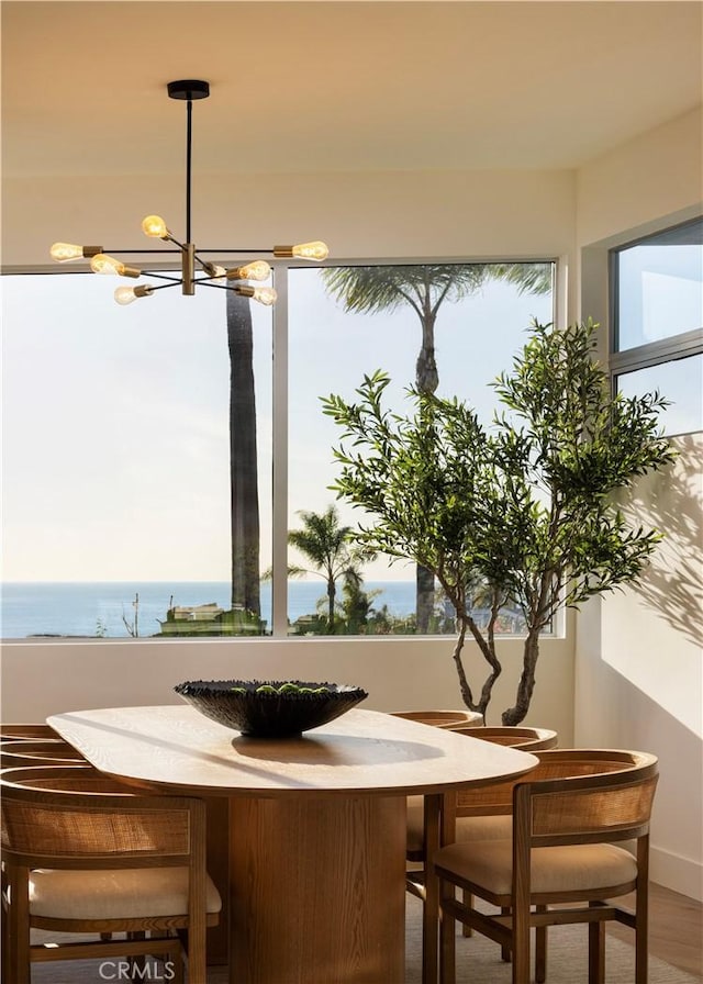 dining room with a chandelier, a wealth of natural light, and a water view