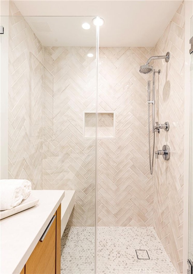 full bath with a tile shower and vanity