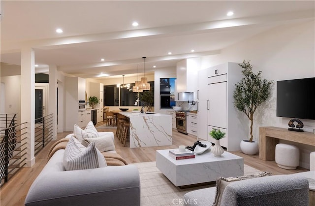 living area featuring recessed lighting, light wood-style flooring, and an inviting chandelier