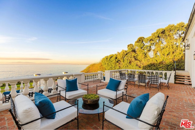 patio terrace at dusk with an outdoor living space and a water view