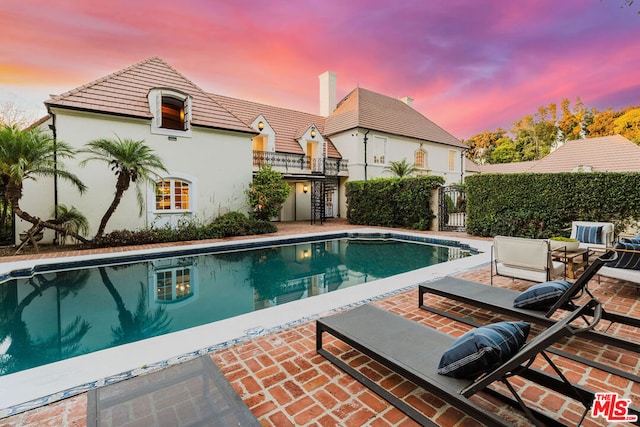 pool at dusk featuring a patio