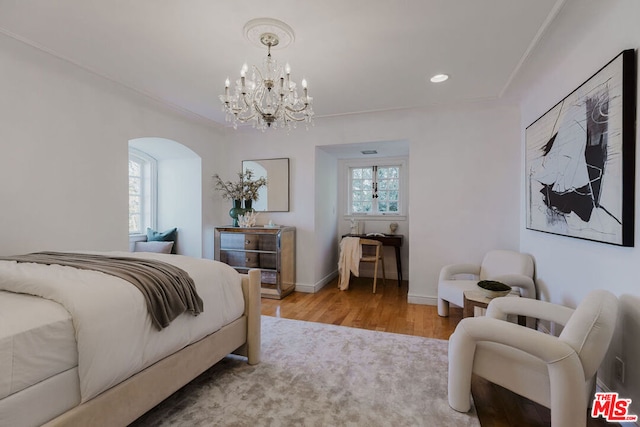 bedroom with light hardwood / wood-style floors, ornamental molding, and a chandelier