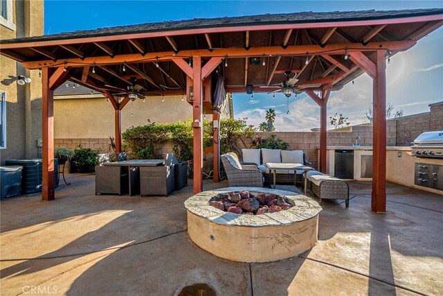 view of patio with ceiling fan, exterior kitchen, a grill, an outdoor living space with a fire pit, and a gazebo