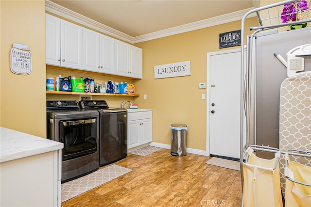 laundry room with cabinets, light wood-type flooring, ornamental molding, sink, and independent washer and dryer