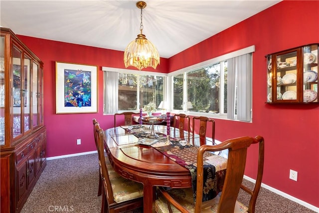 carpeted dining area with a chandelier