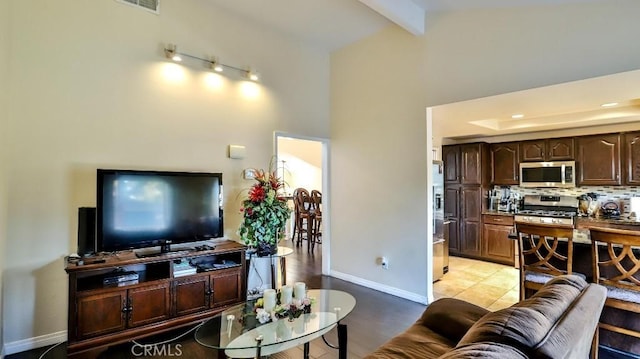 living room featuring beam ceiling, light tile patterned floors, and a towering ceiling