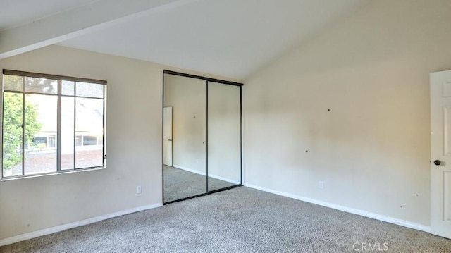 unfurnished bedroom with lofted ceiling with beams, carpet floors, and a closet