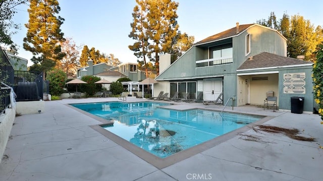 rear view of house with a fenced in pool, a balcony, and a patio