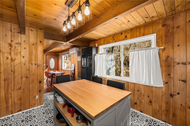 dining room featuring beam ceiling, wood walls, and wood ceiling