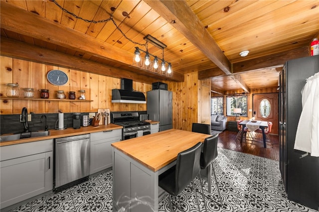 kitchen with sink, stainless steel appliances, wall chimney range hood, butcher block countertops, and white cabinets